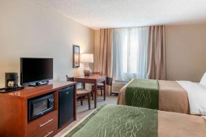 a hotel room with a bed and a desk with a television at Comfort Inn Medford North in Medford +24 photos