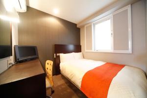 a bedroom with a bed and a desk and a television at Vessel Inn Hiroshima Ekimae in Hiroshima
