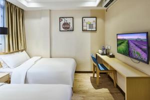 a hotel room with two beds and a desk with a tv at Insail Hotels Guangzhou XiMenKou Subway Station Branch in Guangzhou