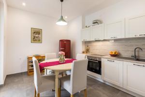 a kitchen with white cabinets and a table and chairs at Apartman Andra in Split