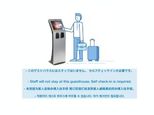 un homme avec ses bagages à une machine à attaque ponctuelle dans l'établissement ABC Guesthouse (1F), à Izumi-Sano