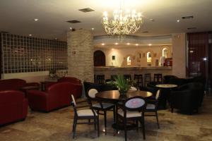 een restaurant met tafels en stoelen en een kroonluchter bij Roseland's Hotel in Marmari