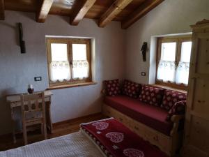 a living room with a couch and two windows at Restor Natura Malga Mondent in Pracorno di Rabbi
