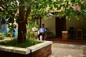 a man sitting in a chair under a tree at Design Ashram in Kozhikode