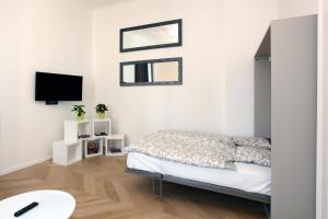 The Apartment House - Mezibranska في براغ: غرفة نوم بيضاء مع سرير وتلفزيون