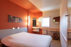 sypialnia z pomarańczowymi ścianami, łóżkiem i umywalką w obiekcie ibis budget Viry-Chatillon A6 w mieście Viry-Châtillon