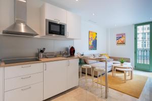 una cucina con armadi bianchi, un tavolo e una sala da pranzo di Apartamentos Miraflores a Málaga