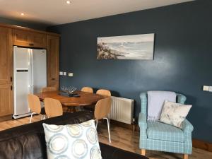 Causeway Coast Cottage في بوشميلس: غرفة معيشة مع أريكة وطاولة وكراسي