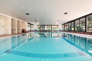 an indoor swimming pool with blue tile floors and windows at Hotel Haliaetum - San Simon Resort in Izola