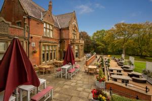 an outdoor patio with tables and chairs and umbrellas at Woodthorpe Hotel in Manchester
