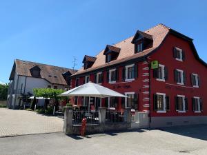 a red building with a white umbrella in front of it at Logis Hôtel Restaurant Au Lion Rouge in Bartenheim