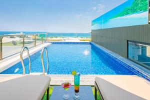 a swimming pool with two drinks sitting on a balcony at Haka Boutique Hotel in Da Nang
