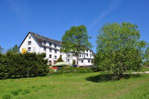 duży biały budynek na wzgórzu z drzewami w obiekcie Hotel Zum Gründle w mieście Oberhof