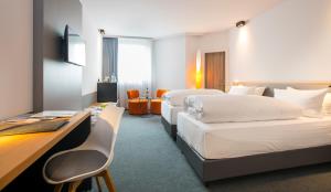 a hotel room with two beds and a desk at Flemings Express Hotel Wuppertal in Wuppertal