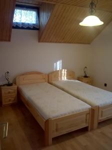 a bedroom with two wooden beds and a window at ZENITH APARTMAN in Gárdony
