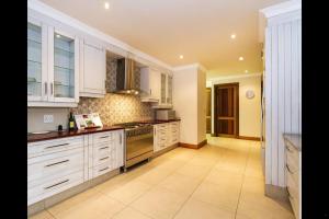 a large kitchen with white cabinets and appliances at 6 On Acacia in Johannesburg