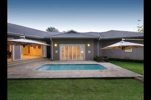 a house with a swimming pool and two umbrellas at 6 On Acacia in Johannesburg