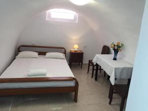 un dormitorio con 2 camas y una mesa con un jarrón de flores en Marcos Rooms, en Oia