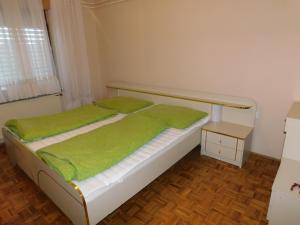 Schlafzimmer mit einem Bett mit grüner Bettwäsche und einem Tisch in der Unterkunft Haus Videm in Videm pri Ptuju