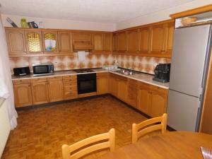 eine Küche mit Holzschränken, einem Tisch und einem Kühlschrank in der Unterkunft Haus Videm in Videm pri Ptuju