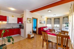 a kitchen and living room with red cabinets and a table at Apartment Medved in Baška
