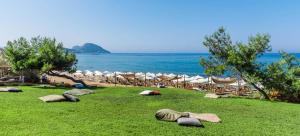 a beach with chairs and umbrellas on the grass at Artemis Suites in Romanós