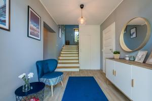 un pasillo con una silla azul y un espejo en Hupkas Apartementy i Pokoje en Jantar