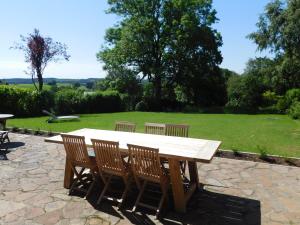 a wooden picnic table with four chairs and a field at L'Aubier in Tenneville