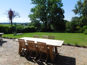 una mesa de picnic de madera con 4 sillas y un campo en L'Aubier, en Tenneville
