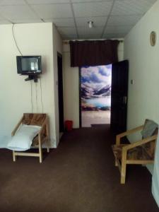 a room with two beds and a flat screen tv at Abbott Hills Guest House in Kāgān
