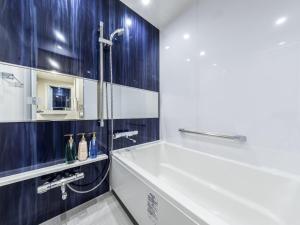 a bathroom with a tub and a sink at Hotel Gracery Osaka Namba in Osaka
