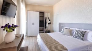 1 dormitorio con 1 cama y un jarrón con flores púrpuras en Little Hotel, en Riccione