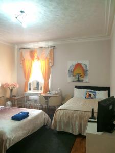 a bedroom with two beds and a table and a window at Gabriel Guesthouse in Rhyl