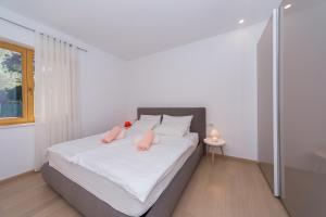 a bedroom with a large white bed with pink pillows at A&J deluxe apartment in Biograd na Moru