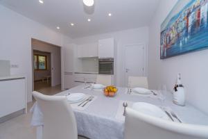 a white dining room with a white table and chairs at A&J deluxe apartment in Biograd na Moru