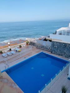 une grande piscine bleue à côté de l'océan dans l'établissement Casa al Mar, à Puerto de Santiago