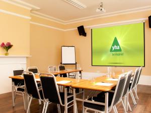 a conference room with a table and chairs and a screen at YHA Stratford-Upon-Avon in Stratford-upon-Avon