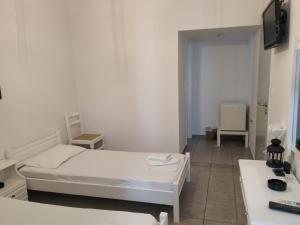 Jest to biały pokój z łóżkiem, biurkiem i umywalką. w obiekcie Sofia w mieście Tinos