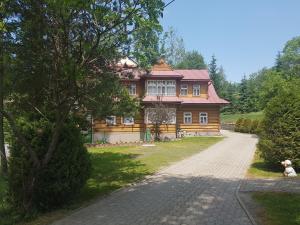 a house with a dog sitting in front of it at Pokoje gościnne u Joanny in Groń