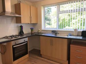 a kitchen with a sink and a stove and a window at Hooton Golf Club in Little Sutton