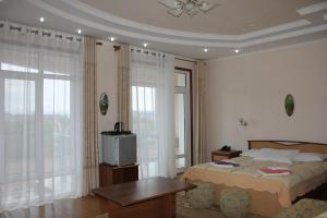 sypialnia z łóżkiem, stołem i telewizorem w obiekcie Tri Korony w mieście Czołponata