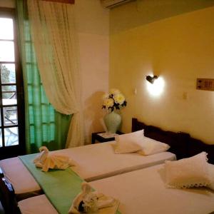 a bedroom with two beds and a vase with flowers at Saint George Hotel in Rodakino