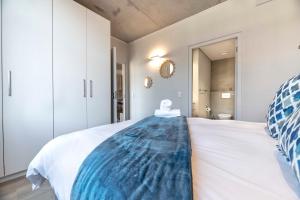 a bedroom with a white bed with a blue blanket on it at C502 Woodstock Quarter in Cape Town