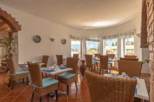 a dining room with tables and chairs and windows at Vila Channa - Adults Only in Albufeira