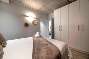a bedroom with a bed and white cabinets at C502 Woodstock Quarter in Cape Town