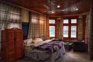 Chitral Guest House في شيترال: غرفة نوم بسرير وخزانة ونوافذ