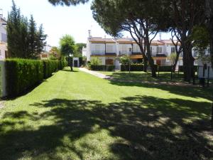 a yard with green grass and trees and buildings at Faro II Holiday Home in Mazagón