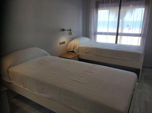 2 camas en una habitación con ventana en Victoria Beach Sunset Lounge, en Cádiz