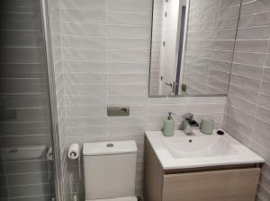 łazienka z toaletą, umywalką i lustrem w obiekcie Victoria Beach Sunset Lounge w Kadyksie