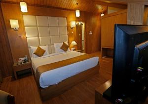 a bedroom with a bed and a flat screen tv at Clarks inn srinagar in Srinagar